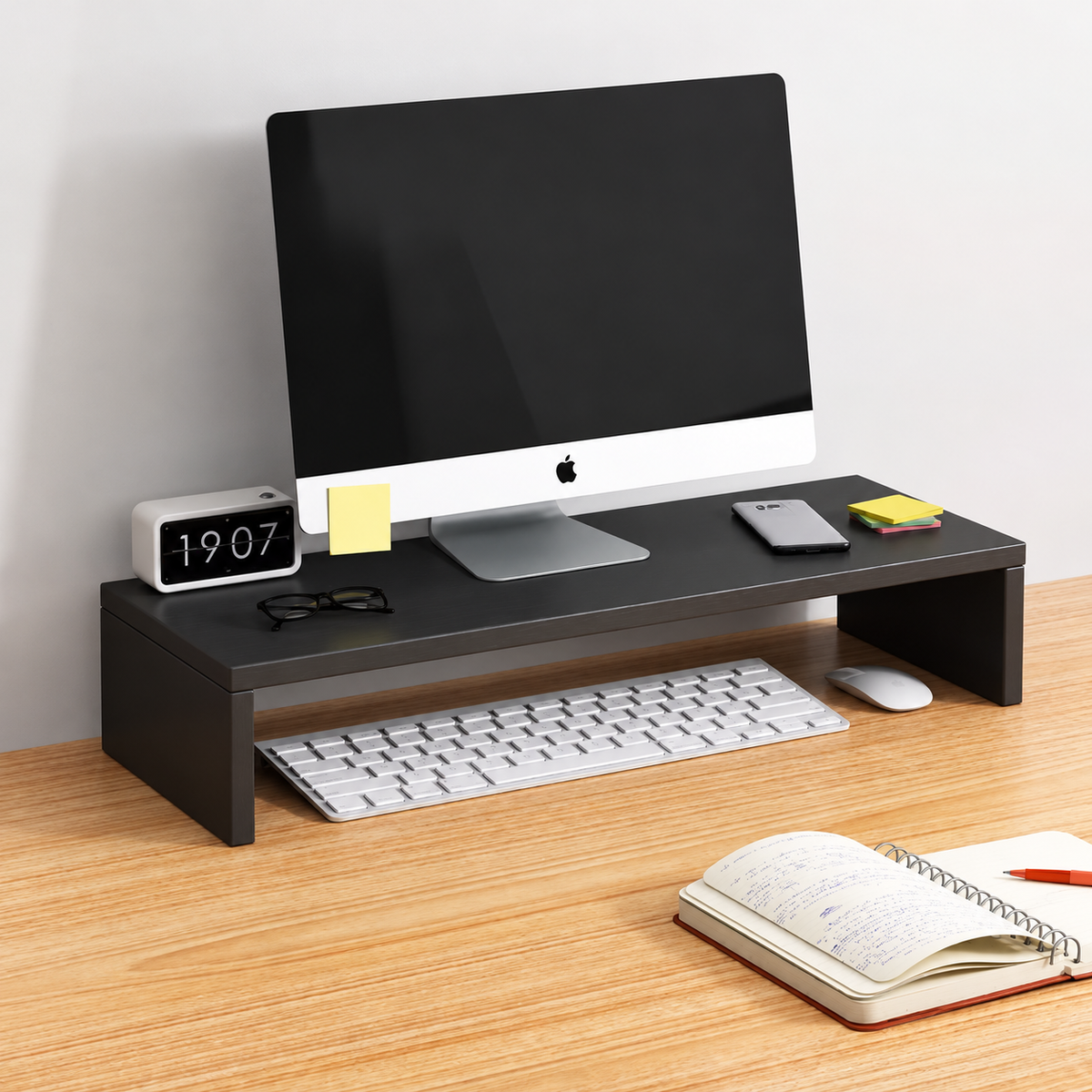 Black desktop monitor riser shown in use; display and desk accessories not included